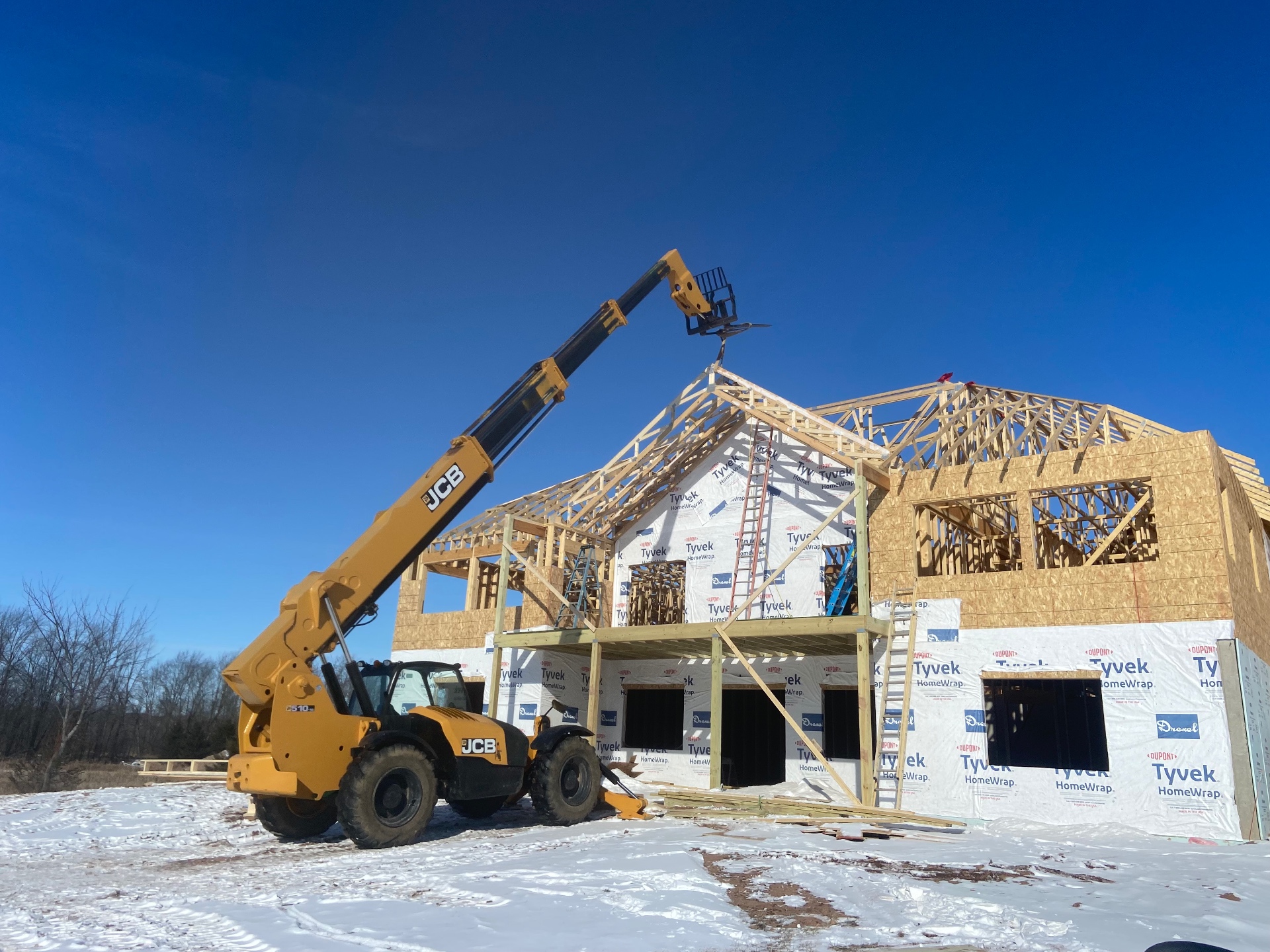 Whole house being framed with roof trusses set by telehandler in Wisconsin